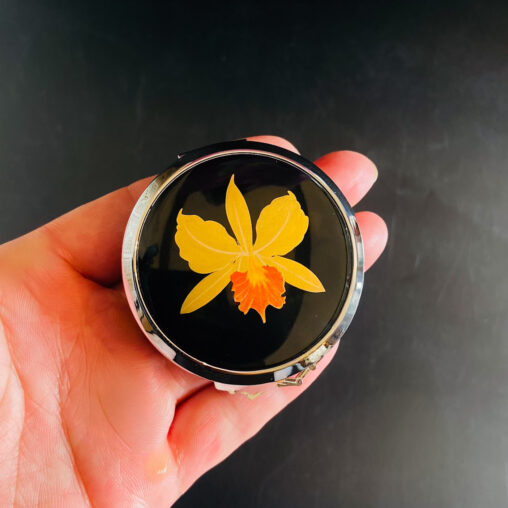 Pink Lady compact with hand-painted orchid design on a black lacquer base (Showa mid-century, 1950s–70s)