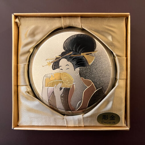 Showa-period chokin metal compact featuring an engraved bijin holding a folding fan
